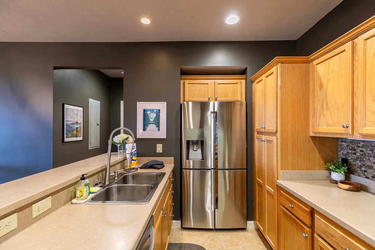 A warm, welcoming kitchen featuring stainless steel appliances, wooden cabinetry, and a spacious sink. The area is well-lit and designed for collaborative cooking and gathering, with ample counter space for meal preparation.