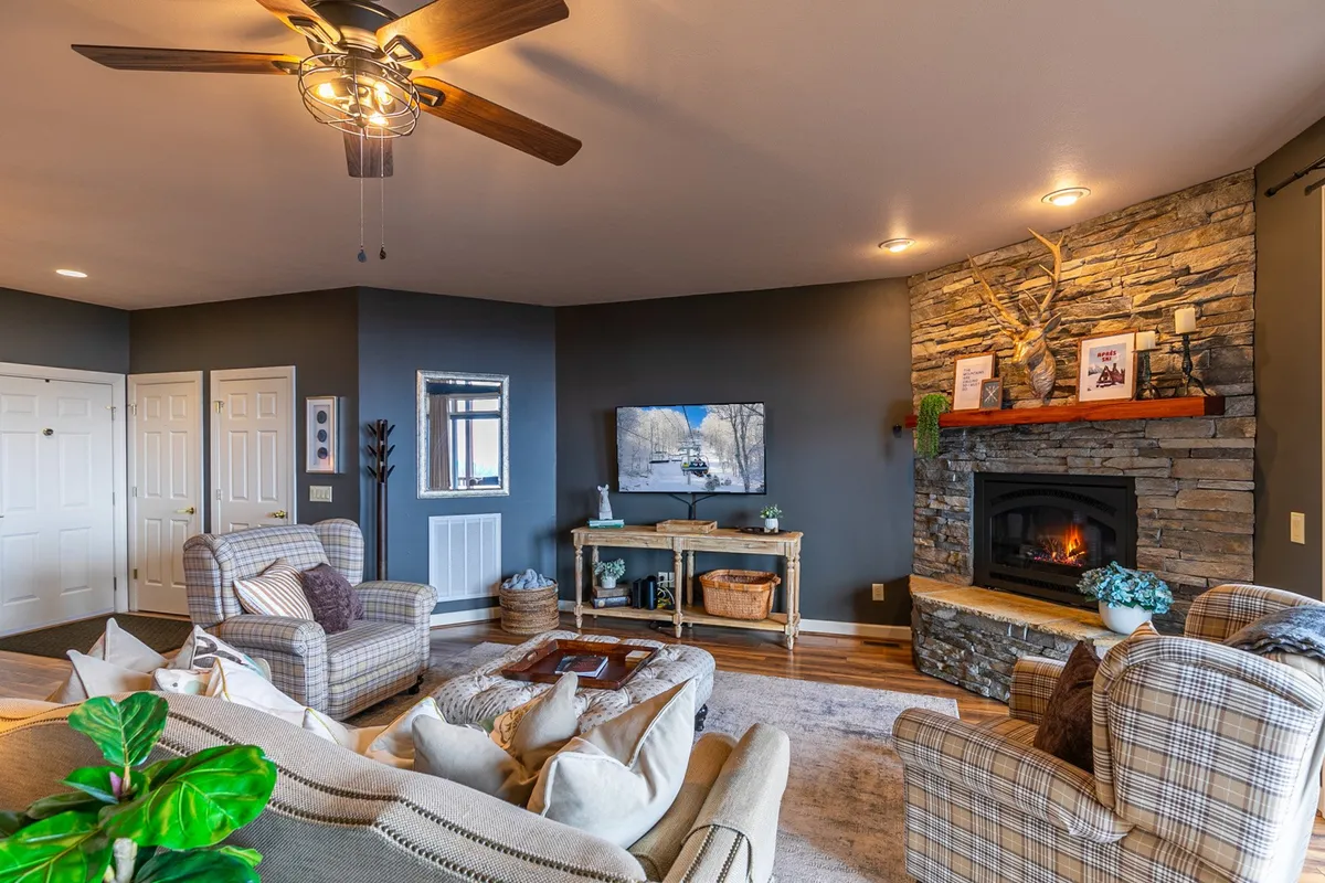 This image captures the living room's core features: a plush seating area arranged around a modern gas fireplace, with a large TV on display. The room exudes warmth and comfort, making it ideal for relaxation, socializing, and movie nights. The decor is tasteful and welcoming, emphasizing the inviting atmosphere described in the section.